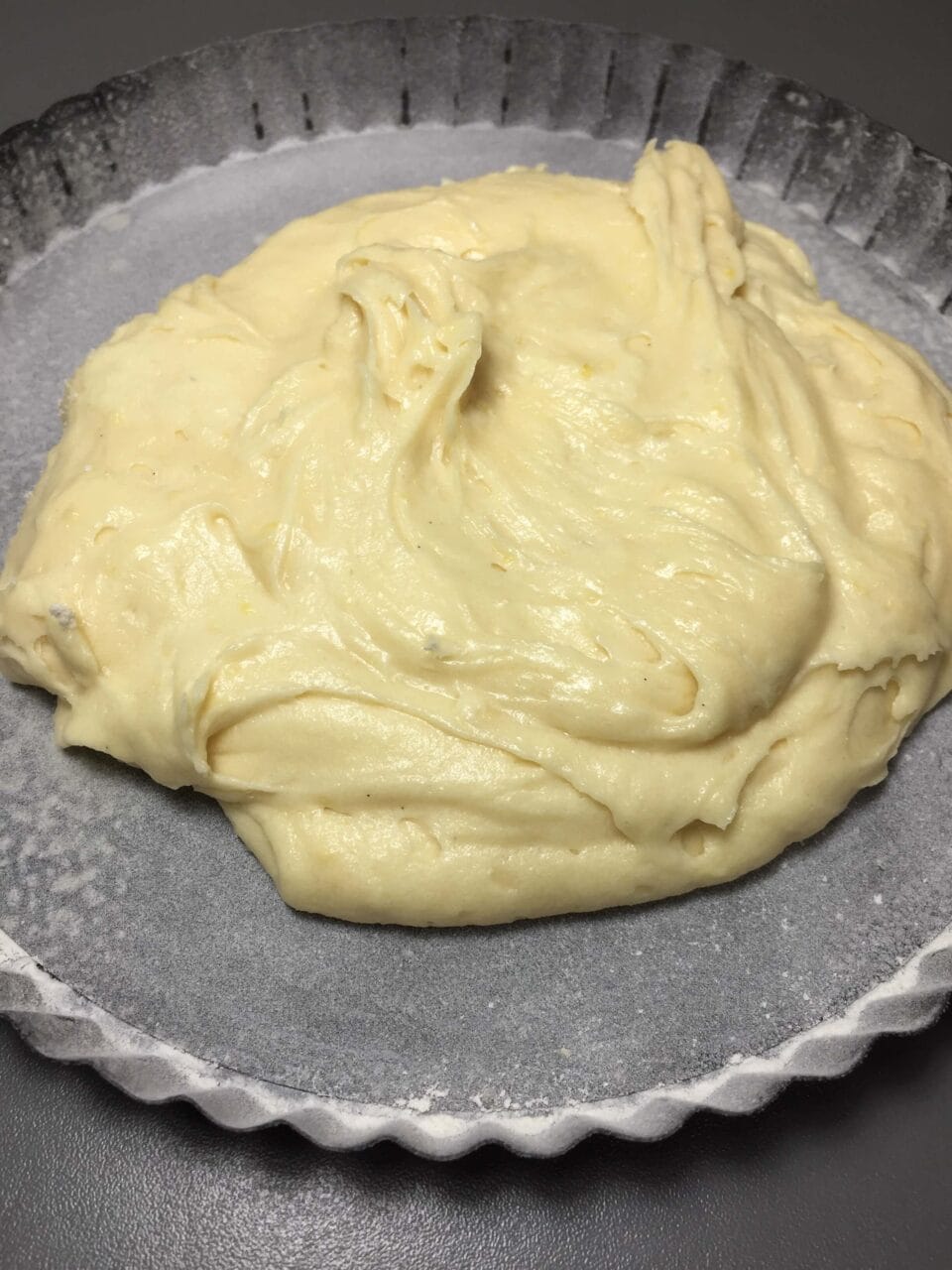 Thick cake batter spread in a fluted baking pan, ready to be baked.